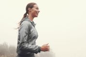 Junge Frau joggt im Nebel Junge Frau joggt im Nebel und trägt ein graues Oberteil